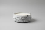 Candle with 'Eleven45' branding on a shelf with other products.